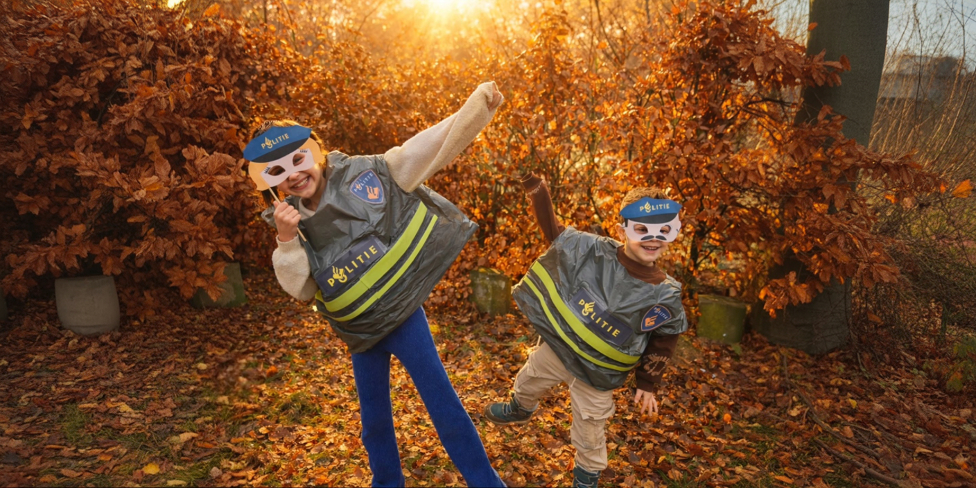 Twee kinderen met politie maskers en hesjes spelen buiten tussen herfstbladeren tijdens een speurtocht kinderfeestje.